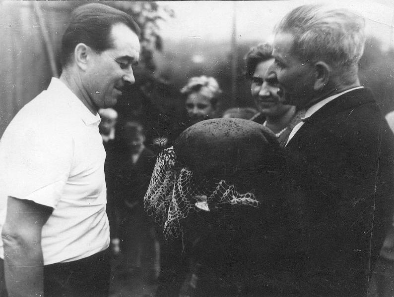 1960-7.jpg - Dożynki  w latach 60. Gospodarz dożynek Paweł Nawrocki przekazuje bochen chleba sołtysowi E. Gniademu
